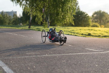 A close up of the handbike athlete on the special bicycle asphalt track in Krylatskie Hills. Evening sunset above the road.