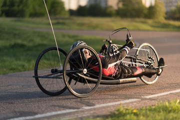 A close up of the handbike athlete on the special bicycle asphalt track in Krylatskie Hills. Evening sunset above the road.