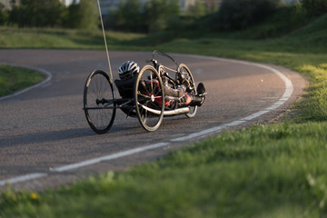 A close up of the handbike athlete on the special bicycle asphalt track in Krylatskie Hills. Evening sunset above the road.