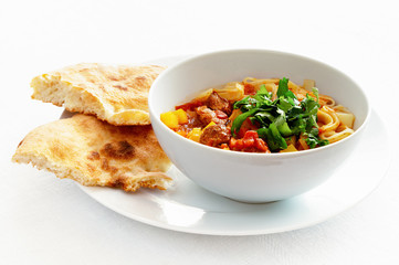 a bowl of lagman with pita