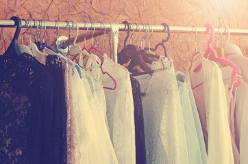 Beautiful women's clothes hang on the hanger in the closet. Toning in the style of instagram. Close-up, soft focus.