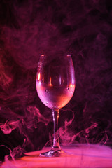 empty glass with pink smoke around on dark background