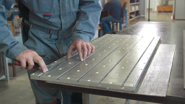 Male hands makes chamfering removing burrs on metal panel with a scraper