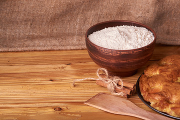 Obraz na płótnie Canvas On a dark wooden table, fashionable bakeries, a bowl with flour, apricot cake and tools stand on table