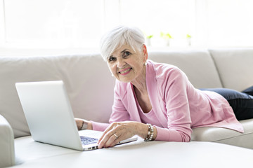 Retired senior woman sitting at home using her laptop