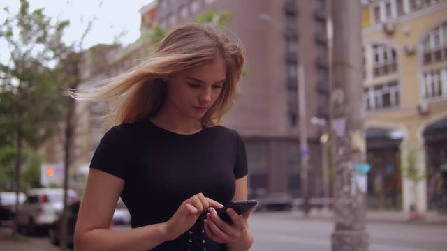 young woman using smartphone walking along the street with driving cars. attractive caucasian businesswoman messaging or chatting online use mobile outdoors