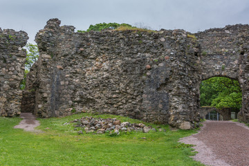Fototapeta na wymiar Torlundy, Scotland - June 11, 2012: One wide and one narrow Pass-through openings in defensive wall inside Inverlochy Castle. Green trees and other gate showing in frame of natural stones.