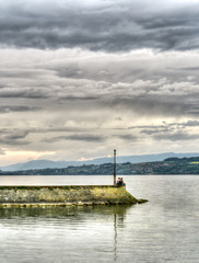 two young lovers at the end of a long pier gazing out over a lake