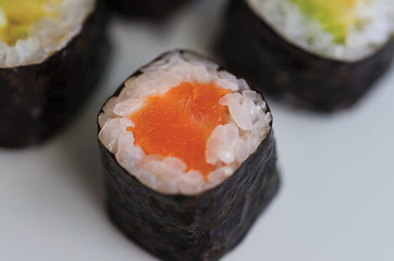 Close up of  Maki sushi on white plate with chopsticks. Sushi Roll of Salmon and avocado. Japanese food ..