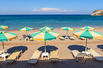 Sun loungers with umbrellas on sandy Kolymbia beach. Rhodes island, Greece
