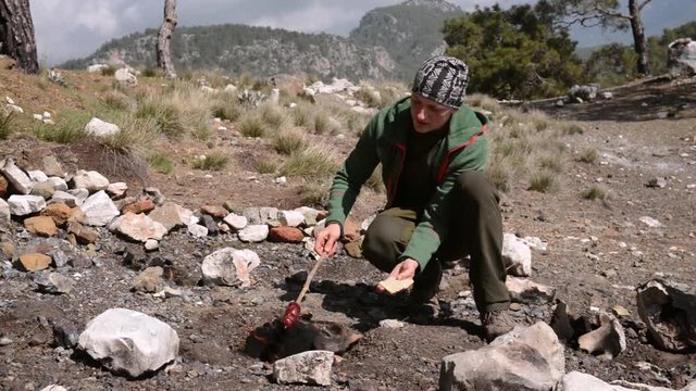Man hiking on Lycian way and cooking on Chimaera eternal flames among the rocks, Turkey