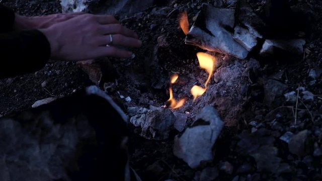 Chimaera flames among the rocks next to green grass and trees. Lycian way, Turkey