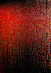 background of glass in the rain with red lighting at night