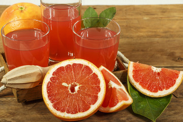Grapefruit juice and fresh grapefruit on a wooden background. Fresh grapefruit juice in a glass bowl, copy space.