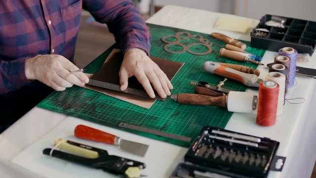 The process of manufacturing a travel case made of genuine leather. Handmade. Man makes markings on the prepackage.