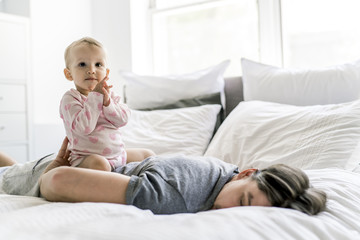 tired father with baby lying on bed at home
