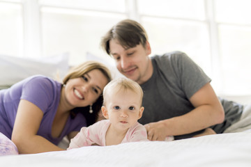 Fototapeta na wymiar Portrait of beautiful young parents and cute baby on bed