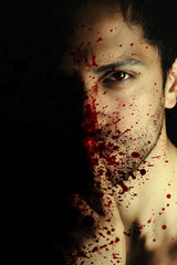 Sexy vampire man with blood on her face on black background