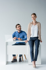 young businessman sitting at workplace while his colleague sitting on his desk on white