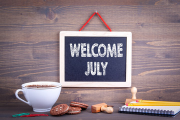 Welcome July, Business Concept. Chalkboard on a wooden background