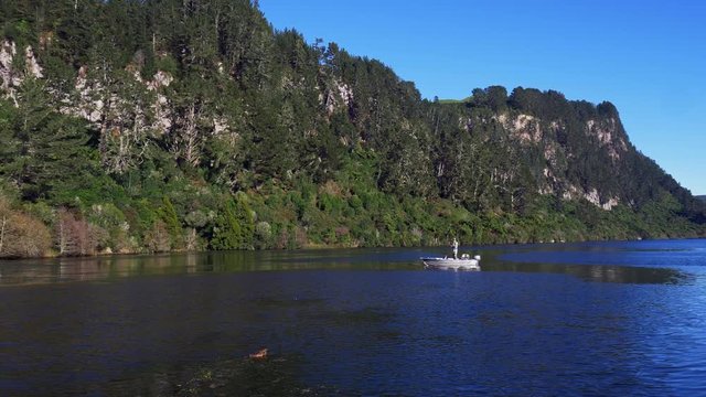 Fly fisherman fly fishing for trout from a boat in Lake Whakamaru near Tokoroa in New Zealand