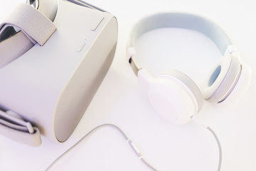 Stylish headphones and VR headset on a white table top view. 
