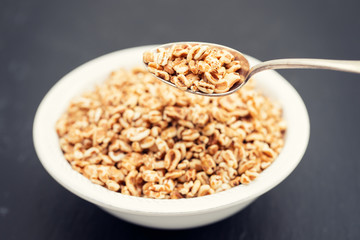 puffed spelt in white bowl on black ceramic background