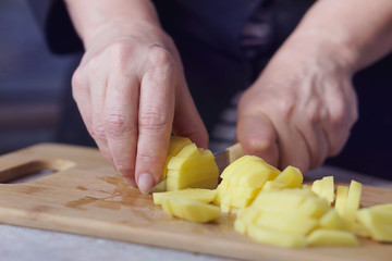 A woman is cutting potatoes
