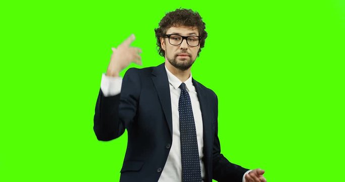 Angry attractive businessman in the glasses, suit and tie throwing documents away on the green screen. Chroma key.