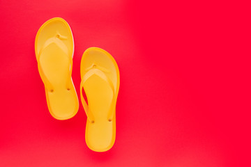 Yellow beach flip flops on neon pink background
