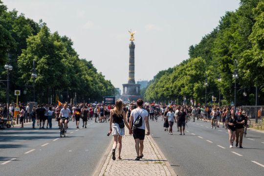 young couple from behind walking towards crowded street parade 