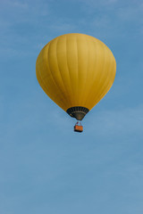 bottom view of yellow hot air balloon flying in blue sky