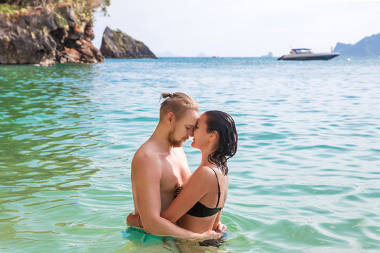 Young slim happy hipster couple on tropical beach kiss each other