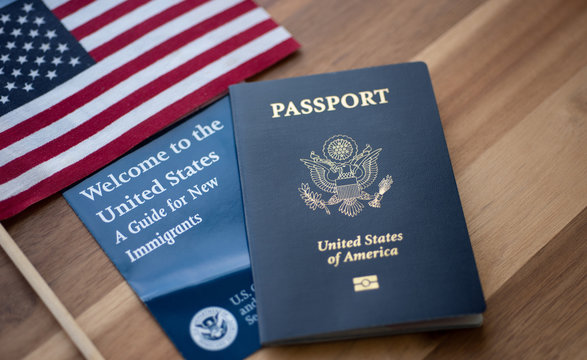 Passport of USA (United states of America) next to a Guide for new Immigrants - Welcome to the United states and American Flag. Wooden Background.
