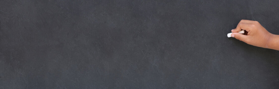 Main d'enfant &eacute;crivant &agrave; la craie sur un tableau noir &agrave; l"&eacute;cole