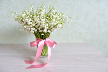 bouquet of wild lily-of-the-valley stands on the table indoors background