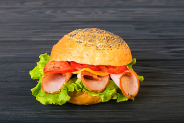 Craft beef burger on wooden table isolated on dark blue background.