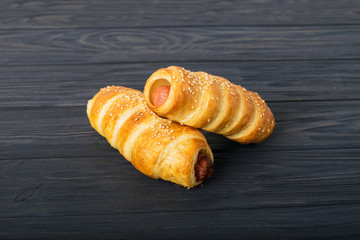 Sausages wrapped in puff pastry. Sausages in a dough on a wooden background