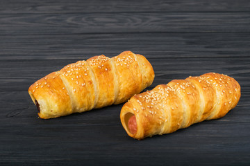 Sausages wrapped in puff pastry. Sausages in a dough on a wooden background