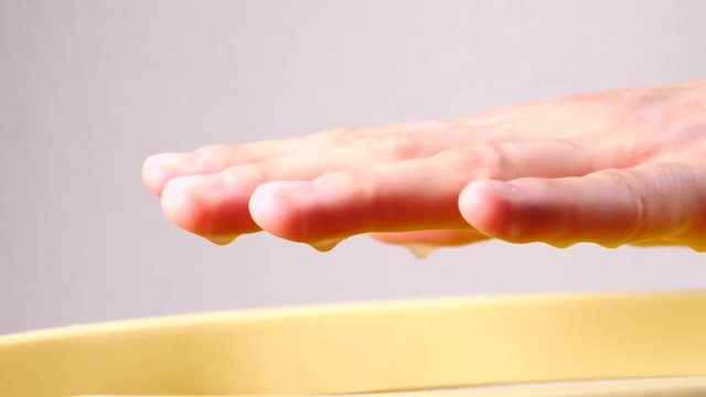 Close up slow motion shot of unrecognizable woman putting hand into paraffin bath taking care of hands skin.