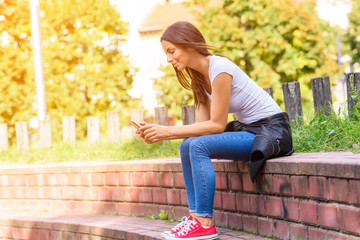 Naklejka premium A young woman using her smartphone in a Park