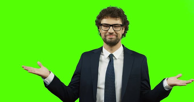 Smiled Caucasian man in suit and tie doing gesture with hands like I don't know or whatever on the green screen background. Chroma key.
