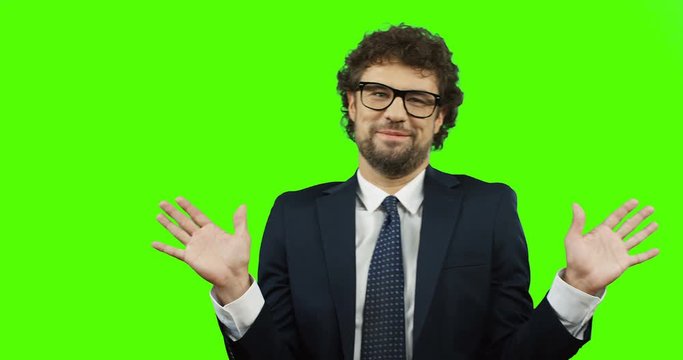Attractive man in the glasses, suit and tie waving hands, saying no and refusing doing something on the chroma key. Green screen.