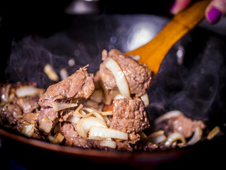 close up wooden stick mixing the meat stew with vegetables with dark background