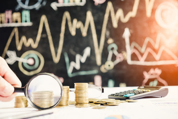 Magnifying glass, pencil and calculator on financial chart and graph, accounting background