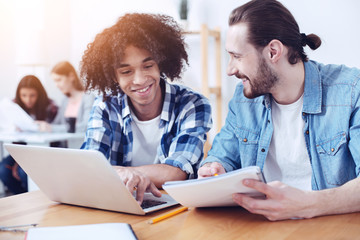 Obraz premium I am happy. Funny boy with curly hair smiling while looking at keyboard and typing text