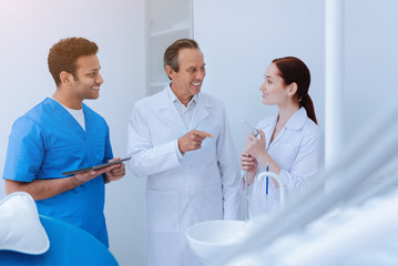Fototapeta premium Your term. Attentive brunette male person wearing blue uniform standing in semi position while keeping his gadget in right hand