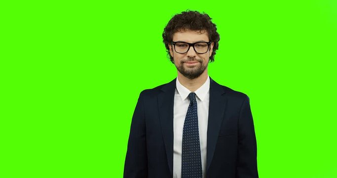 Portrait shot of the handsome Caucasian man in the business style of clothing turning his head to the camera and smiling. Green screen. Chroma key.