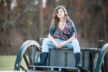 Young woman sitting manspreading womanspreading spreading legs on old cannon carriage in Manassas National Battlefield Park in Virginia where Bull Run battle was fought - obrazy, fototapety, plakaty