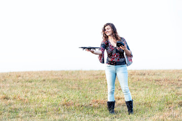 Young happy smiling woman controlling video camera drone holding, touching it in autumn or fall with boots in park in Virginia countryside open field hill